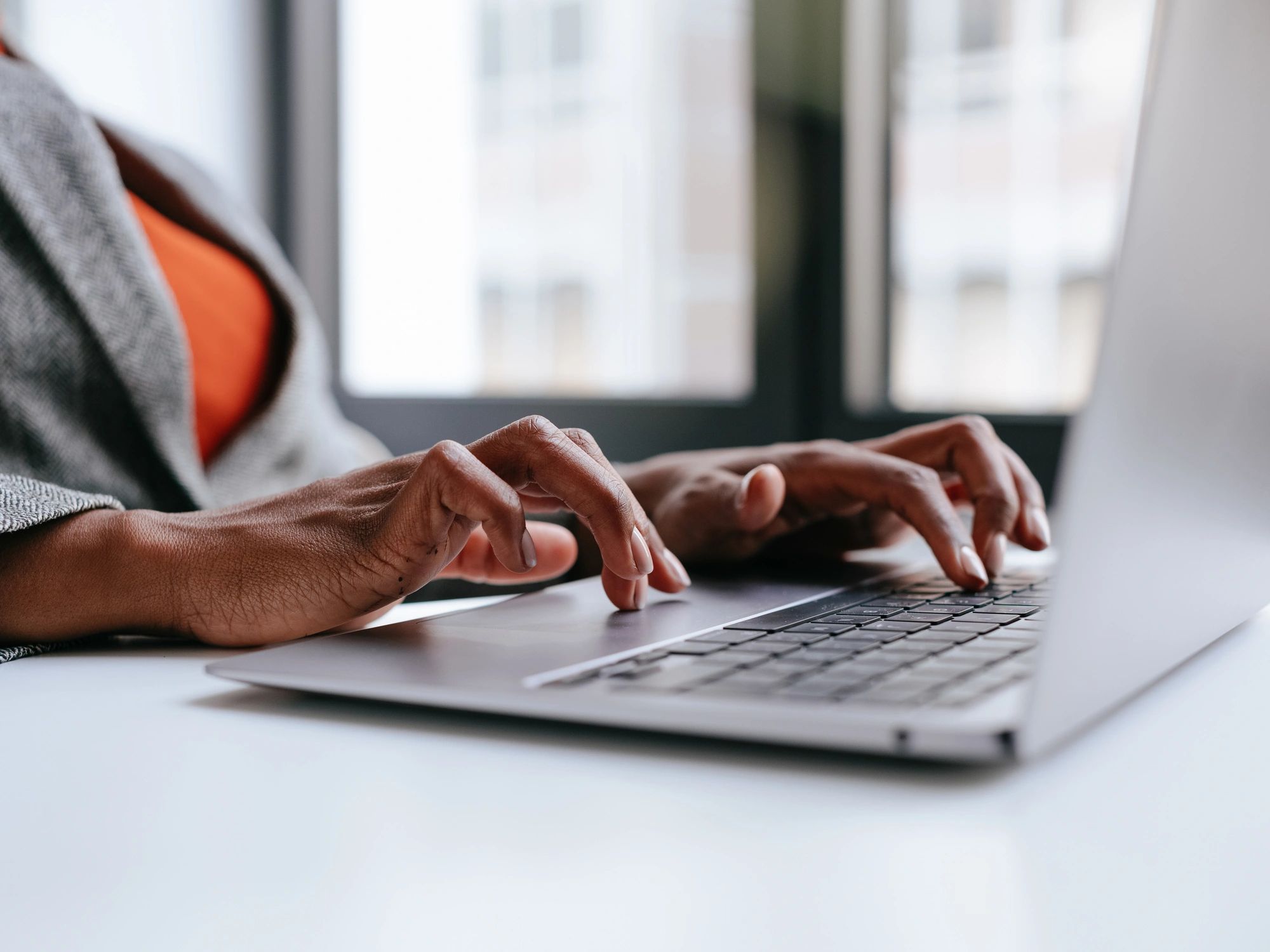 Hands typing on a laptop in a modern workspace